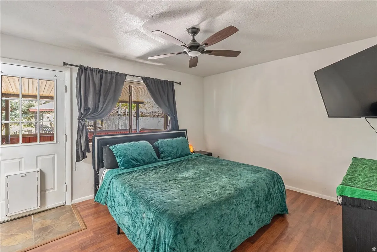 Bedroom with wood finished floors, a textured ceiling, and ceiling fan