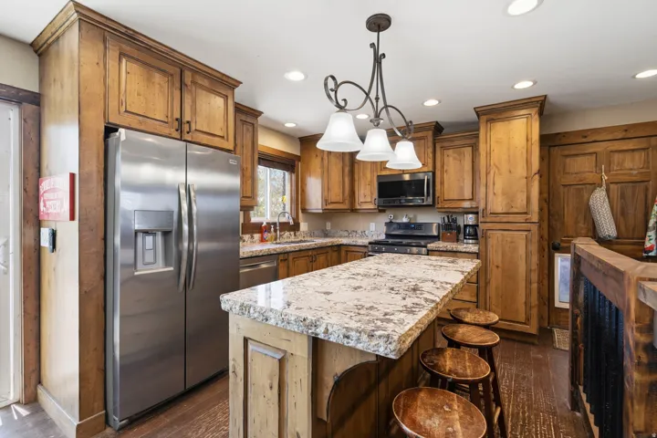 Kitchen with stainless steel appliances, hanging light fixtures, a kitchen island, wood finish cabinets, and a breakfast bar
