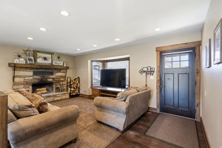 Living area with hardwood / wood-style flooring, recessed lighting, and a stone fireplace