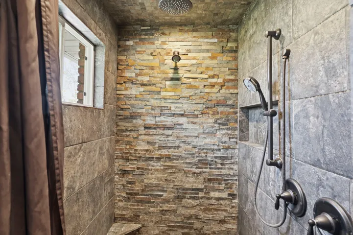 Full bath featuring a rock/tile shower