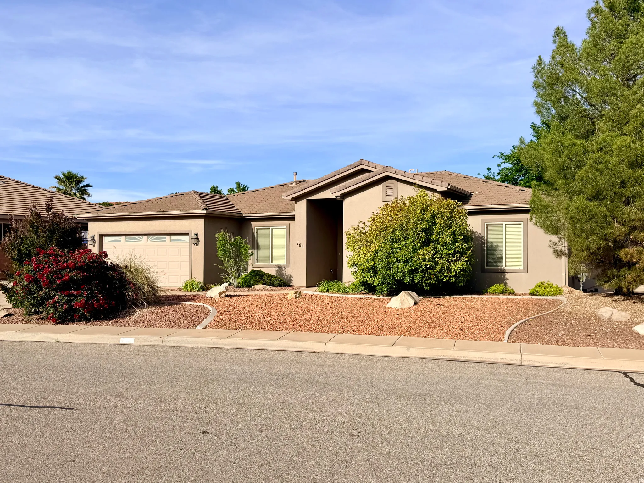 Ranch-style home with stucco siding, an attached garage, and a tiled roof