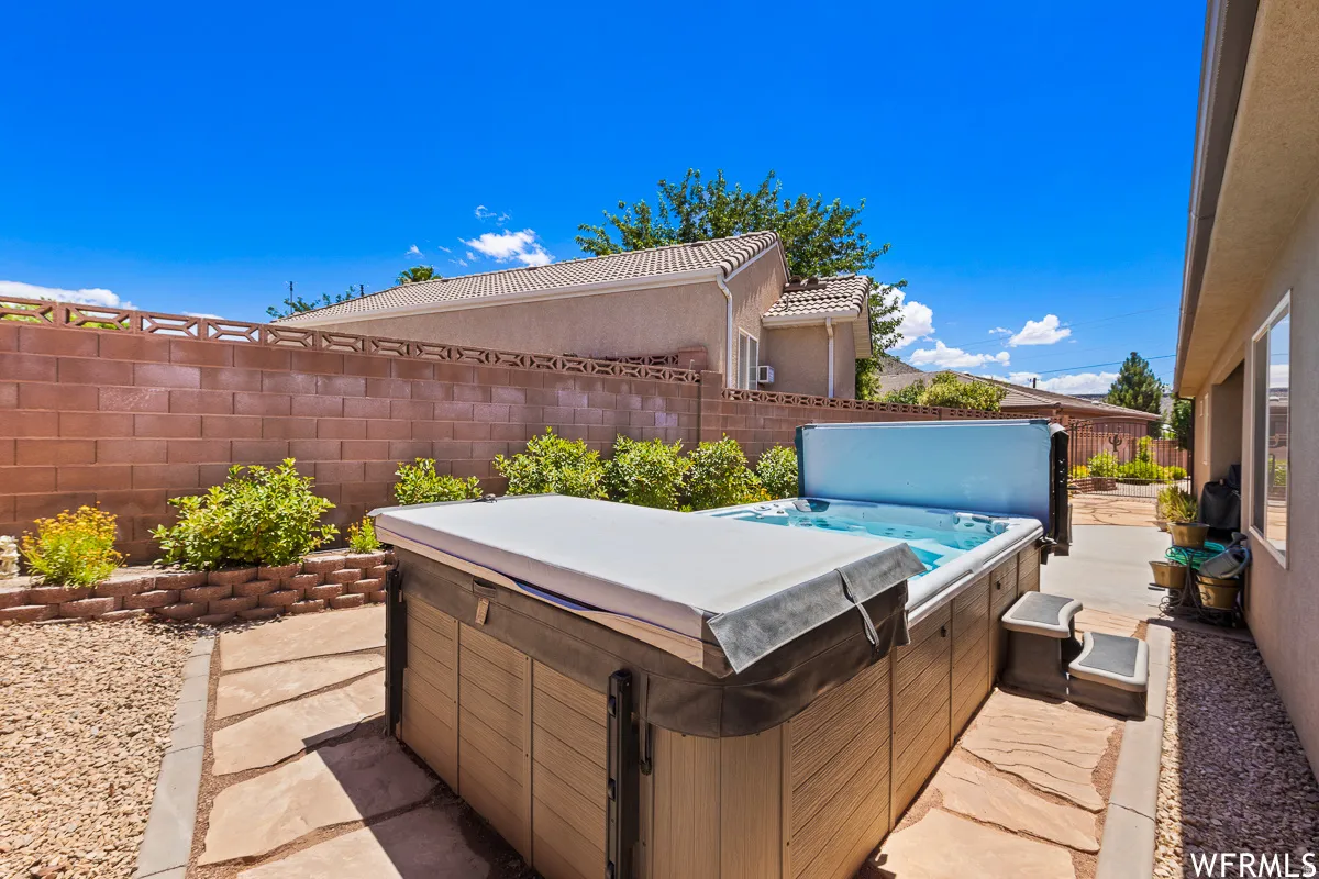 Fenced backyard featuring a hot tub