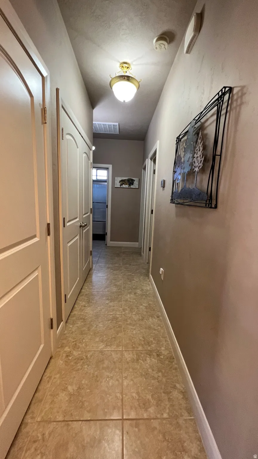 Hall with baseboards and light tile patterned floors