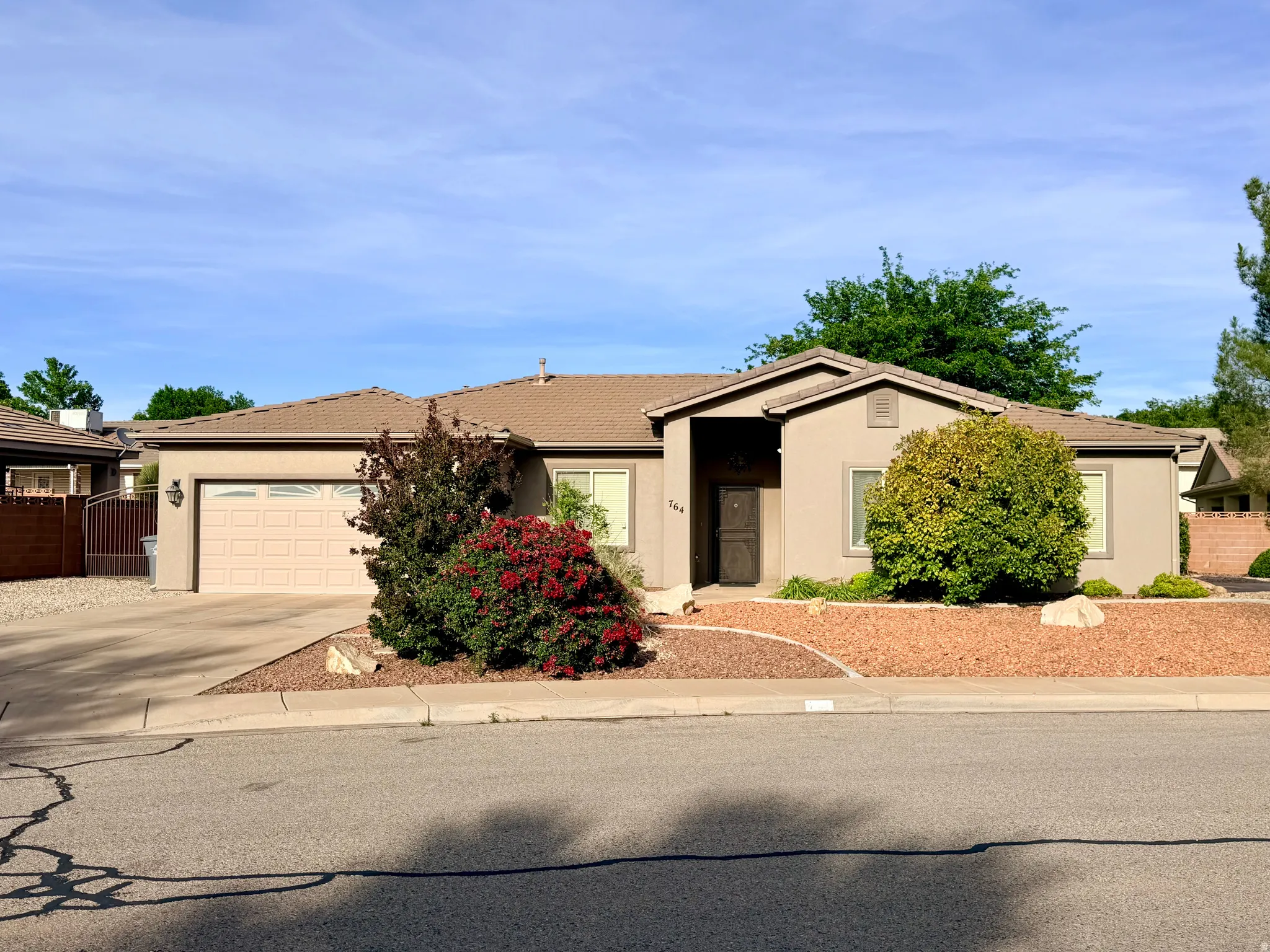 Ranch-style home with stucco siding, driveway, a garage, and a tile roof