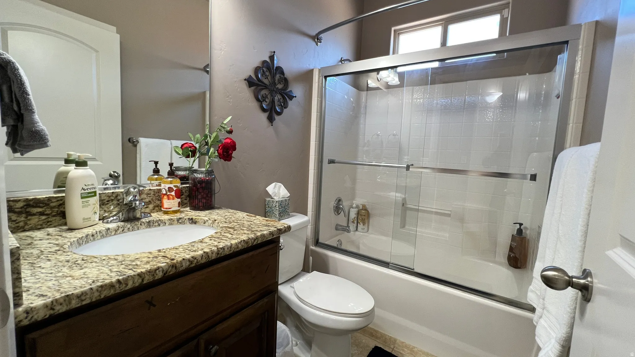 Full bathroom featuring vanity, shower / bath combination with glass door, and a textured wall