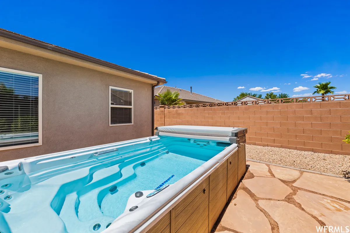 View of pool featuring a fenced backyard, a hot tub, and patio surround