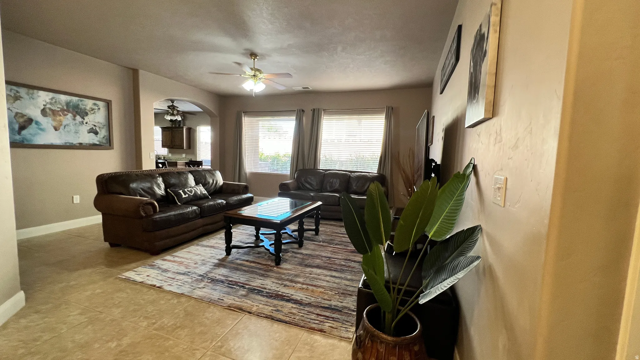 Living room featuring ceiling fan, light tile patterned flooring, and arched walkways