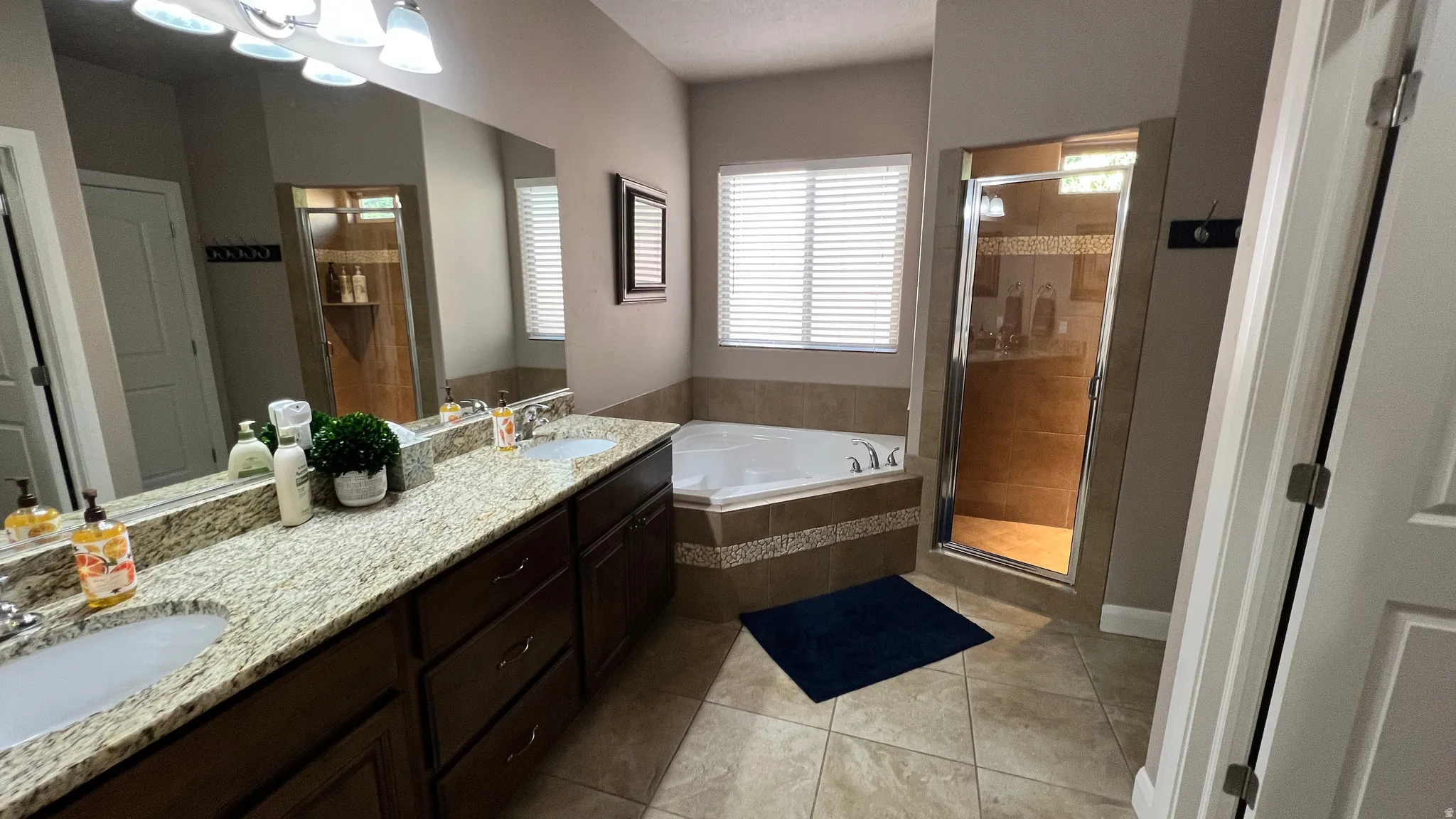 Full bathroom featuring a stall shower, double vanity, a bath, and light tile patterned floors