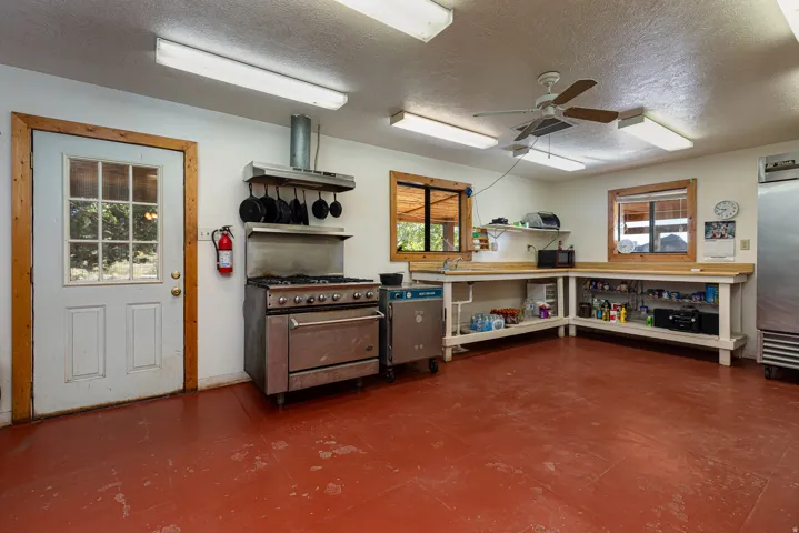 Kitchen with a textured ceiling, ceiling fan, high end appliances, and ventilation hood