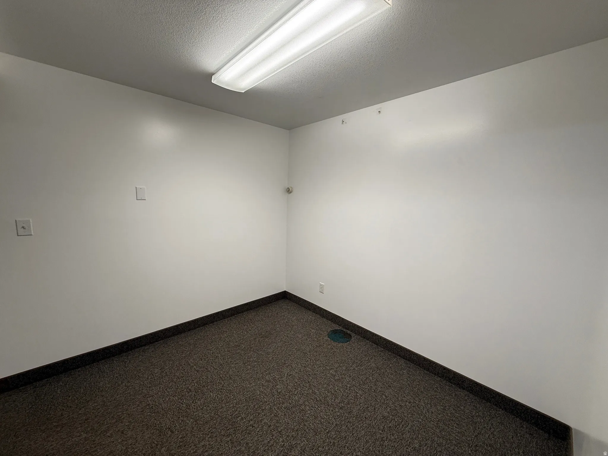 Spare room featuring dark colored carpet and a textured ceiling