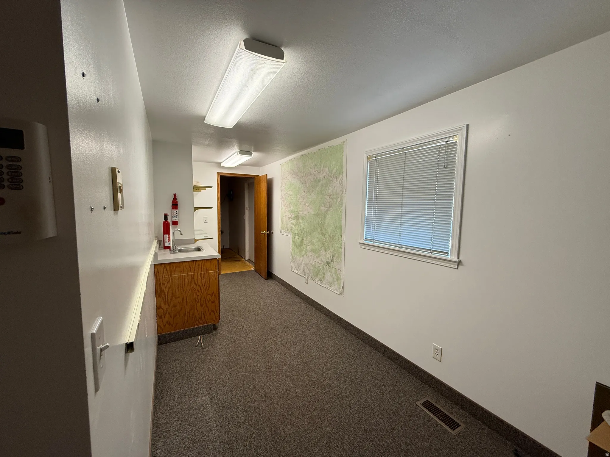 Hall featuring dark colored carpet and a textured ceiling
