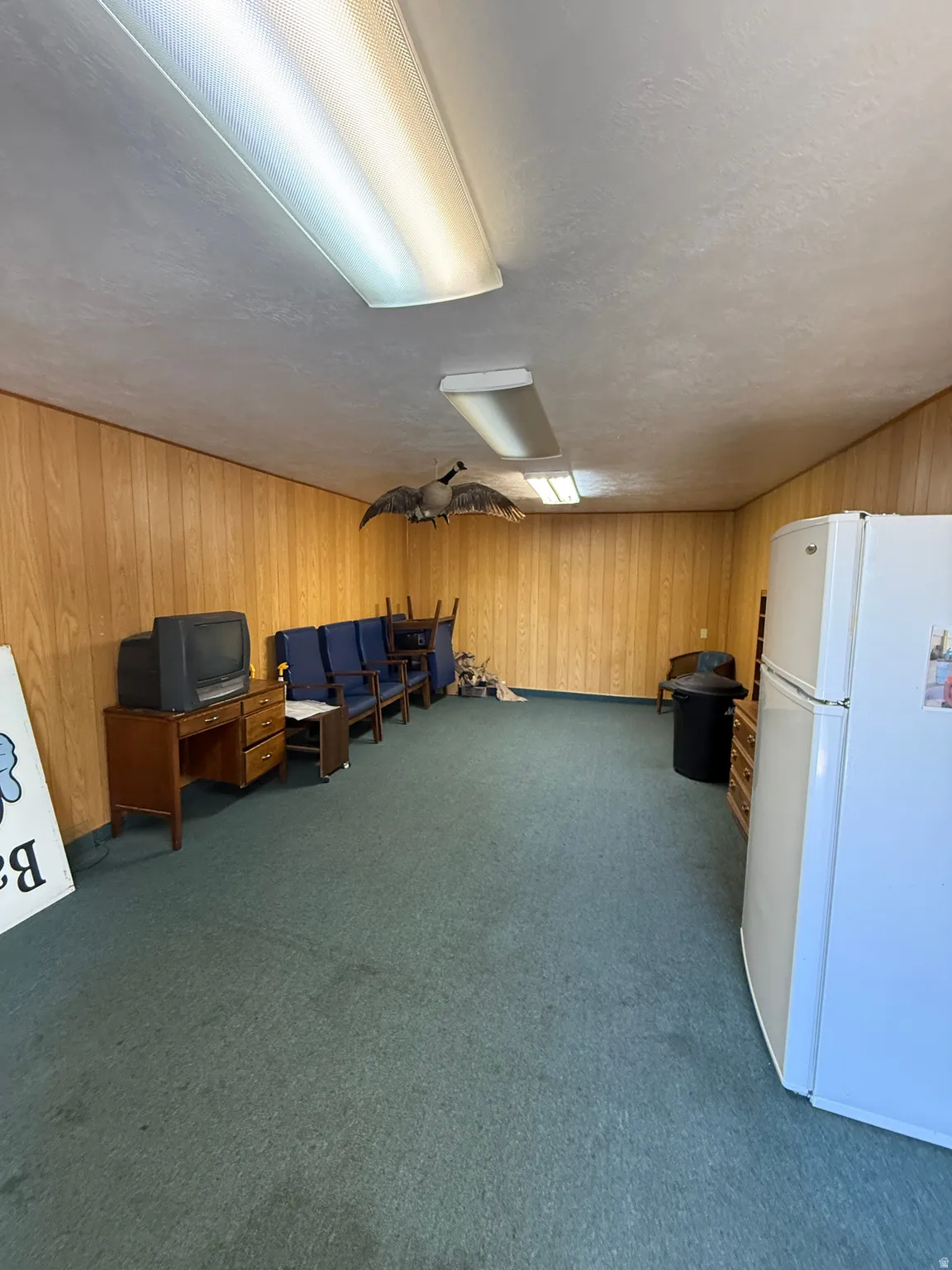 Miscellaneous room with dark colored carpet, wooden walls, and a textured ceiling