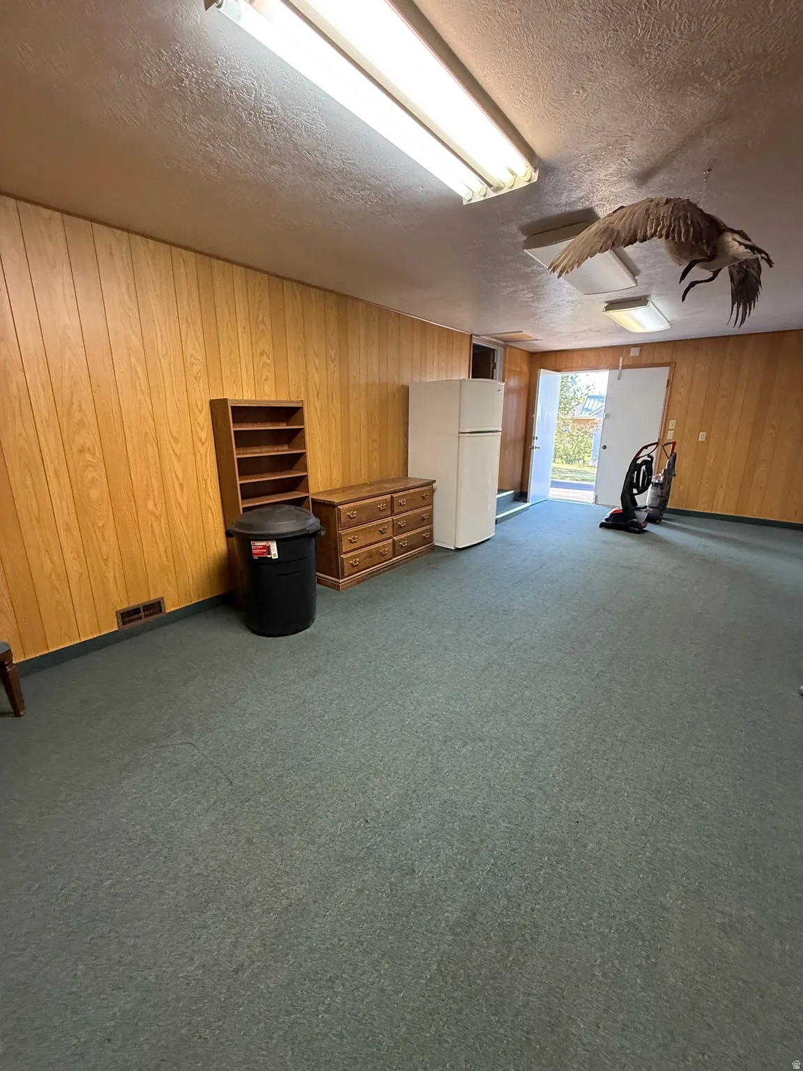 Misc room featuring wood walls, dark colored carpet, and a textured ceiling