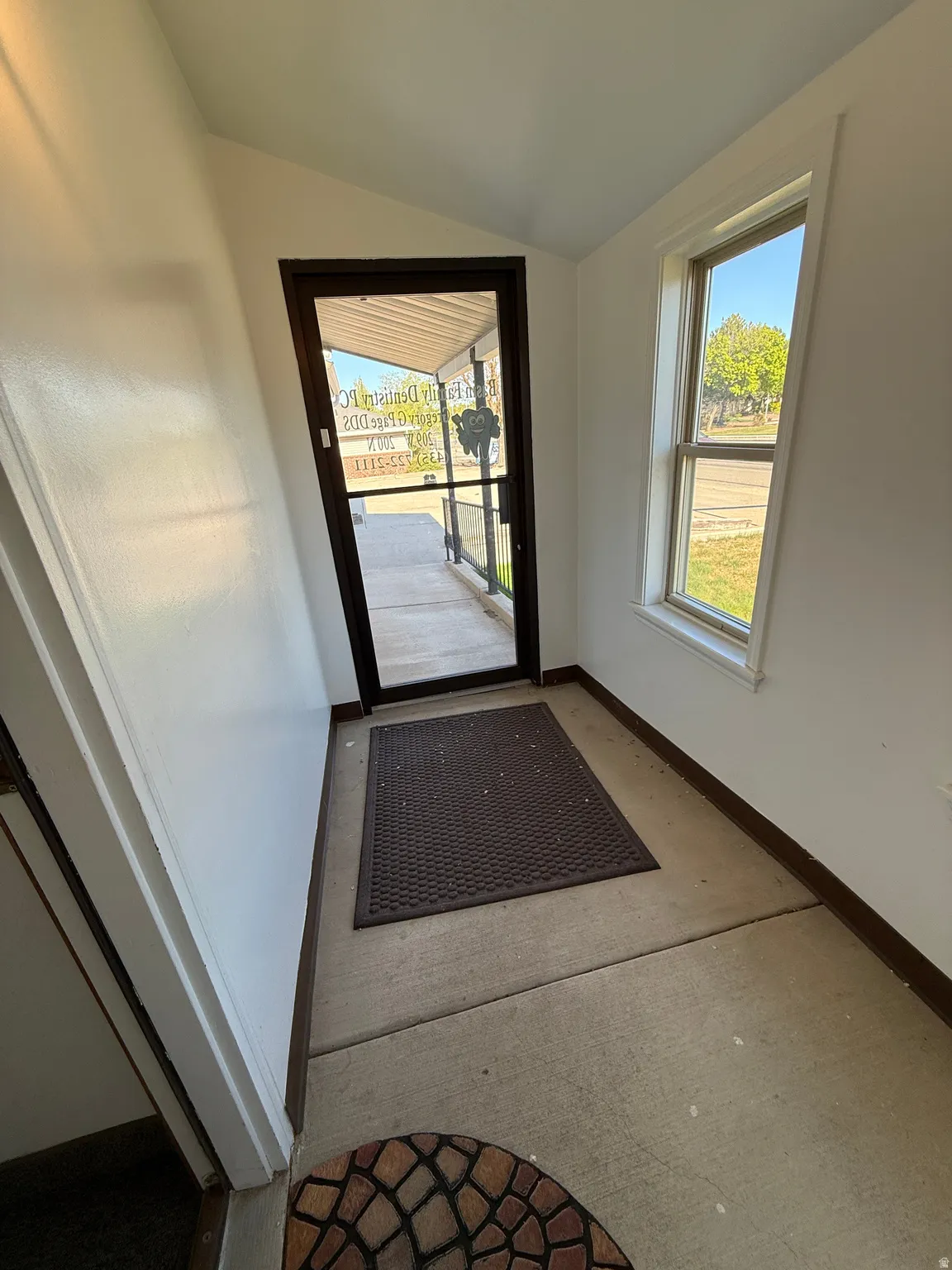 Doorway to outside with baseboards and vaulted ceiling