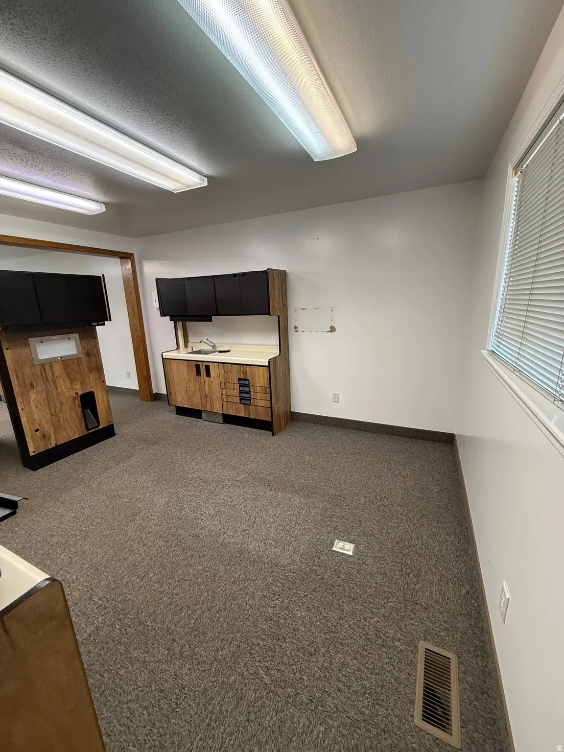 Unfurnished living room featuring dark colored carpet and a textured ceiling