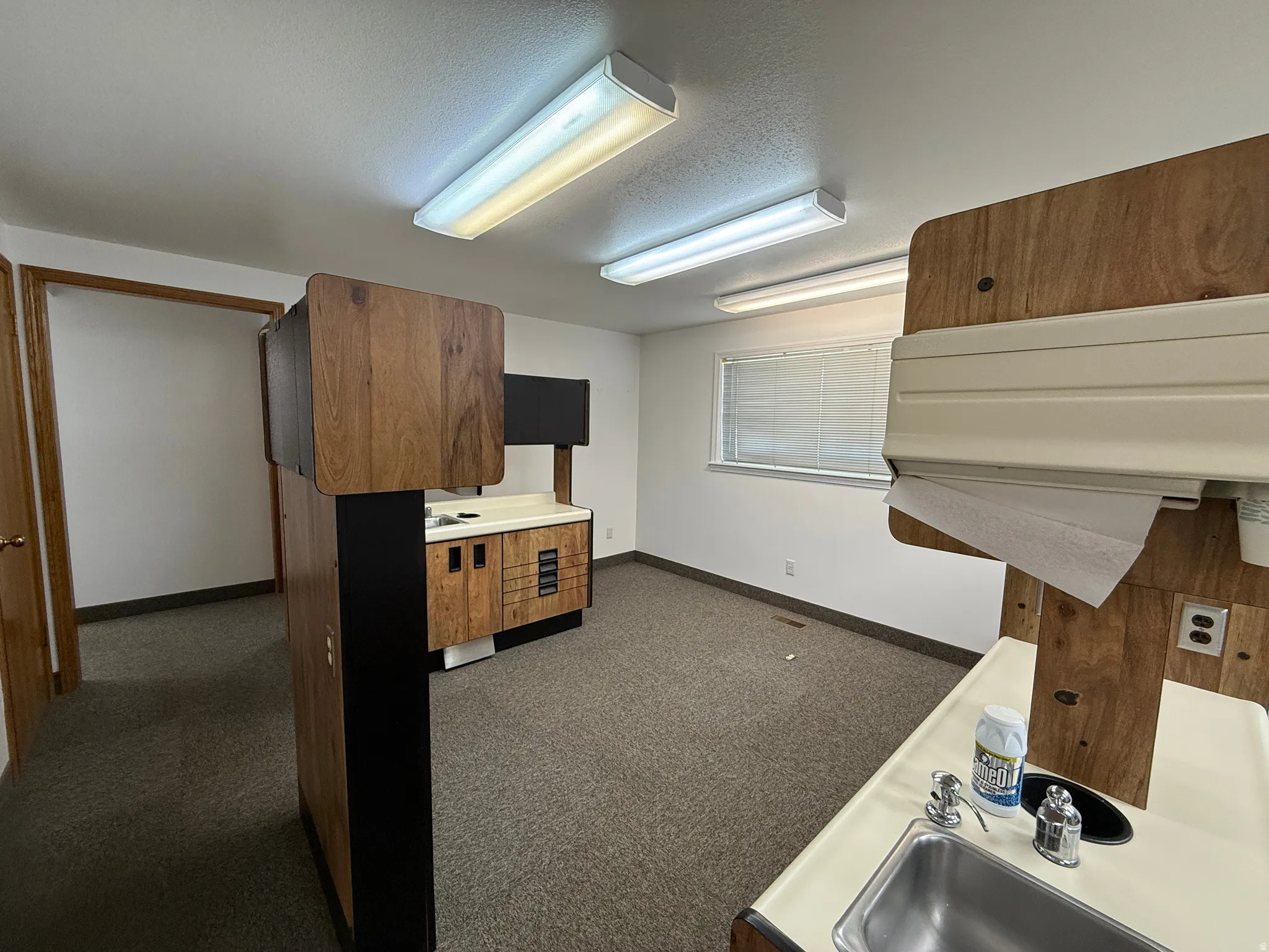 Kitchen featuring wood finish cabinetry, light countertops, dark carpet, and a textured ceiling