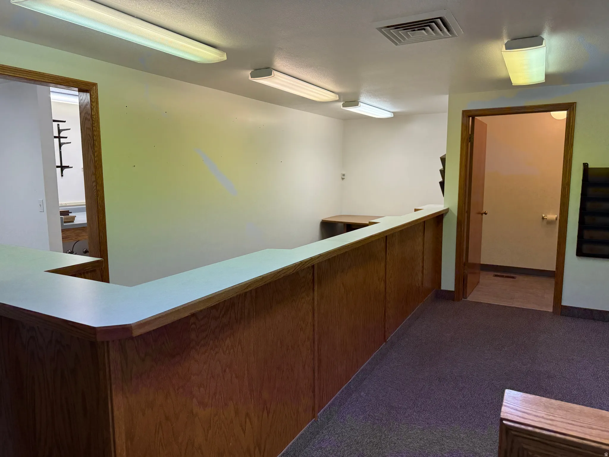 Hallway with dark colored carpet and baseboards