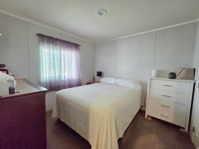 Bedroom with dark colored carpet and crown molding