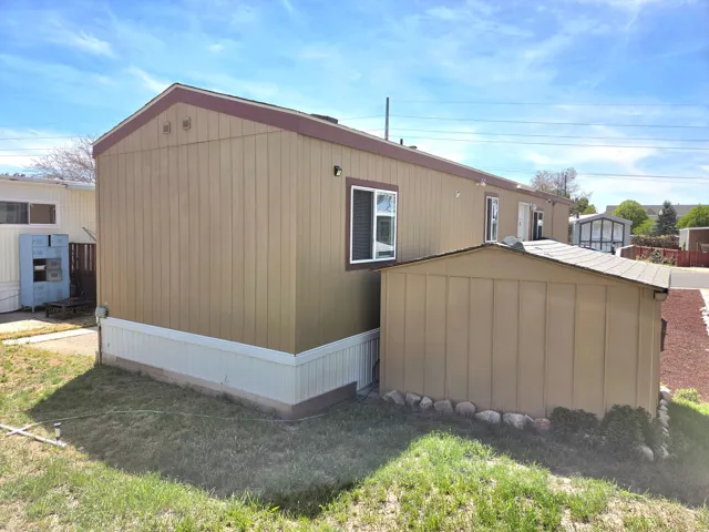 View of property exterior featuring a storage unit and a lawn