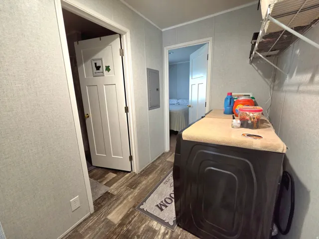 Laundry area with washer / clothes dryer, dark wood finished floors, ornamental molding, and electric panel