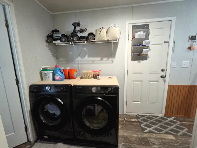 Laundry area featuring independent washer and dryer, dark wood-style flooring, wood walls, a wainscoted wall, and ornamental molding