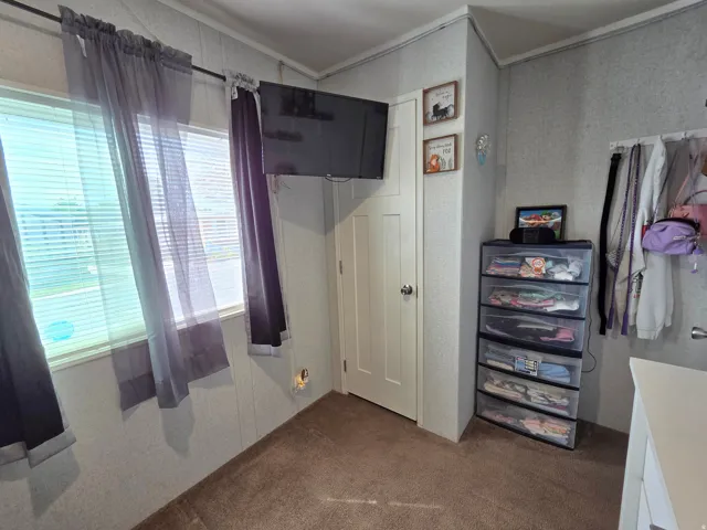 Bedroom with dark colored carpet, crown molding, and a closet