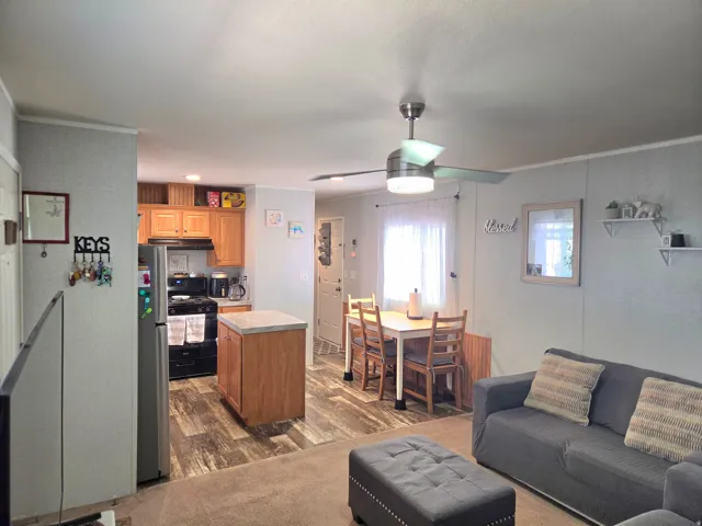 Kitchen with a center island, crown molding, freestanding refrigerator, black range with gas cooktop, and wood finish cabinets