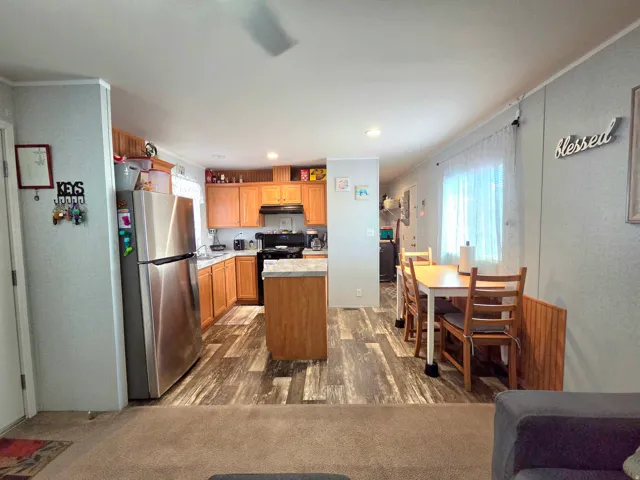 Kitchen featuring freestanding refrigerator, light countertops, a kitchen island, gas stove, and dark wood finished floors