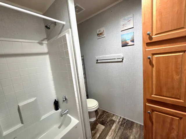 Full bathroom with dark wood finished floors and shower / bathtub combination