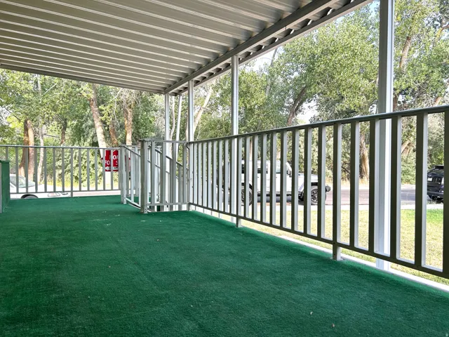 Covered porch featuring a green outdoor carpet, metal railing, and a matching metal roof