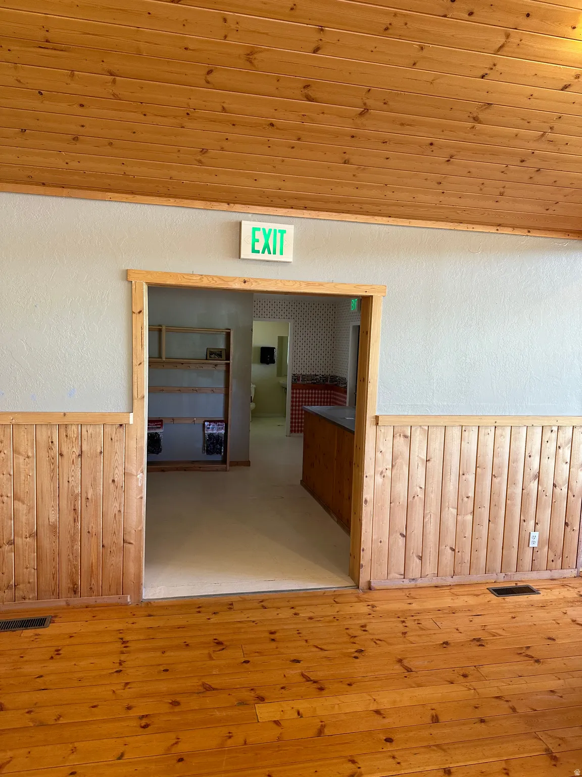 Hall with wooden walls, wainscoting, hardwood / wood-style floors, a textured wall, and wood ceiling