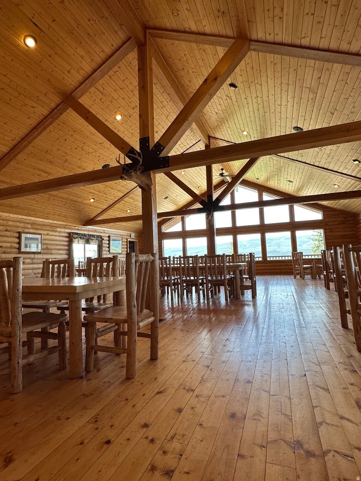 Dining space featuring light wood finished floors, rustic walls, and a high wooden beamed ceiling