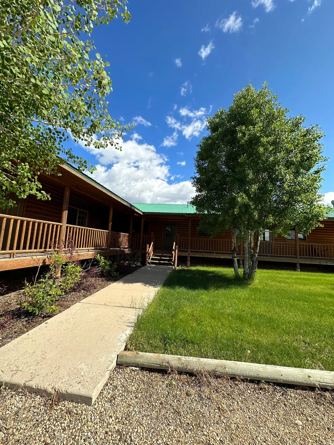 Log-style house featuring a porch, a front lawn, and a metal roof
