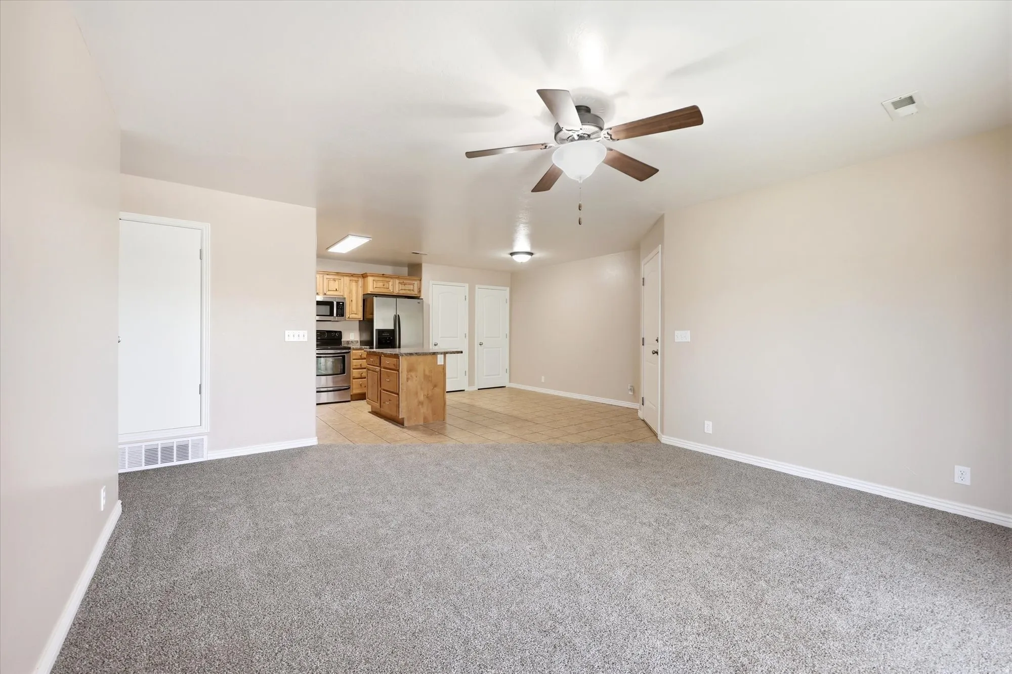 Unfurnished living room with ceiling fan and light carpet