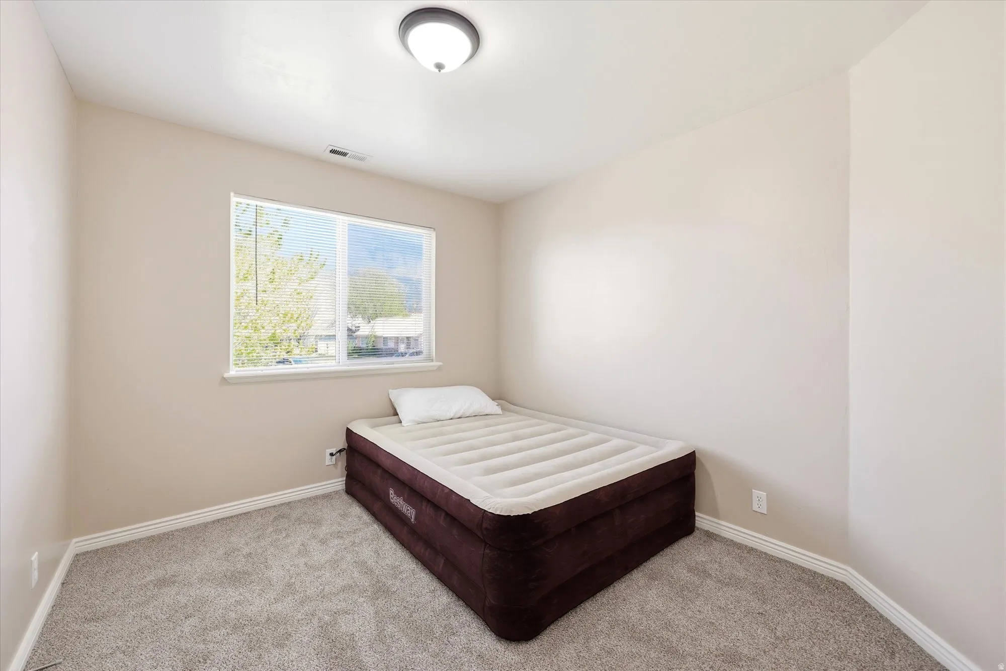 Bedroom featuring light carpet and baseboards
