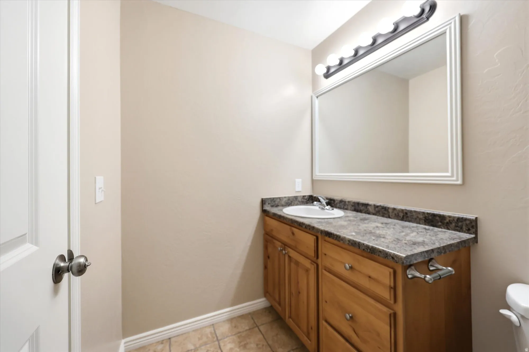 Bathroom with vanity, light tile patterned flooring, and a textured wall