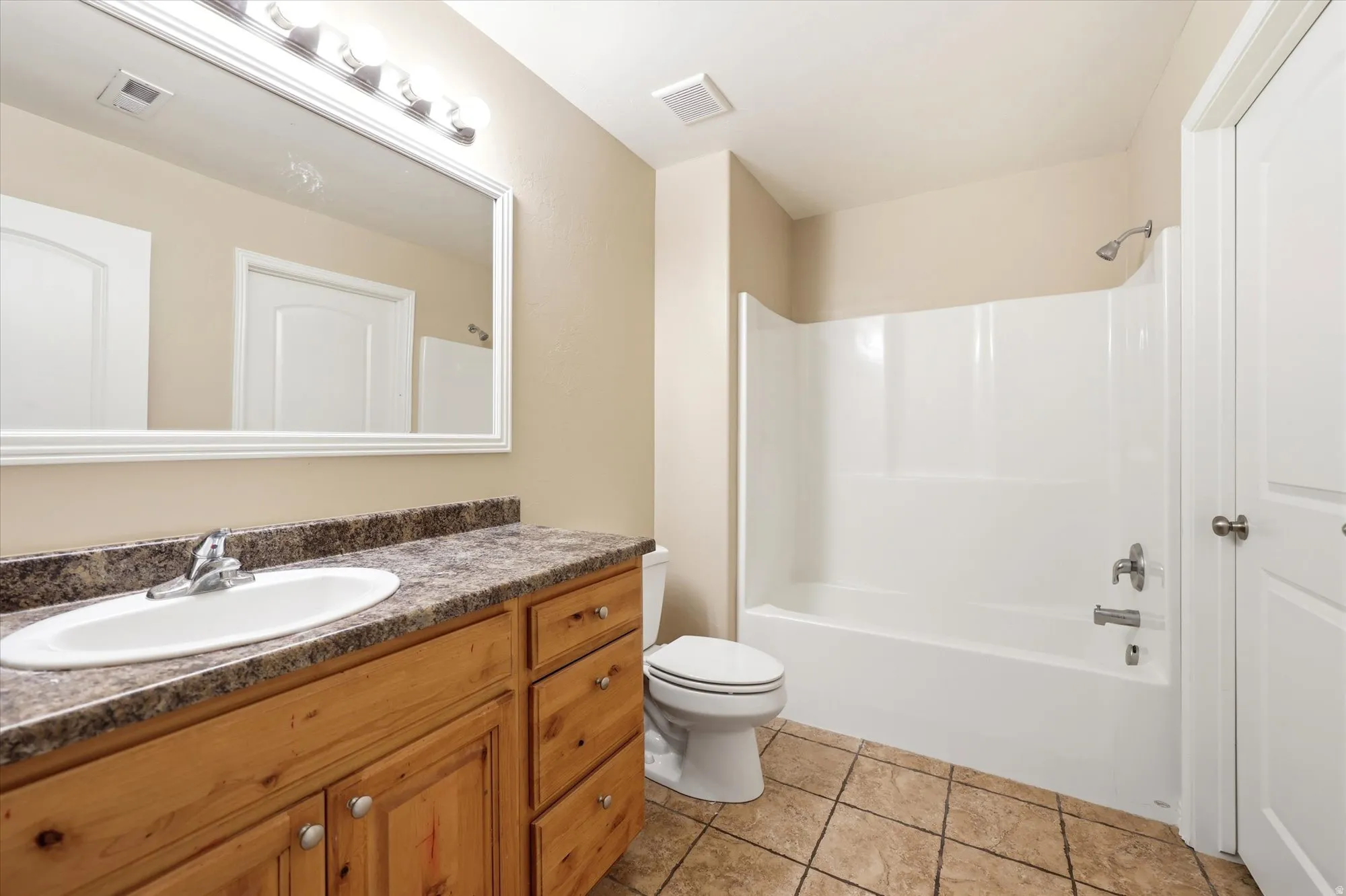 Full bathroom with vanity, light tile patterned floors, and washtub / shower combination