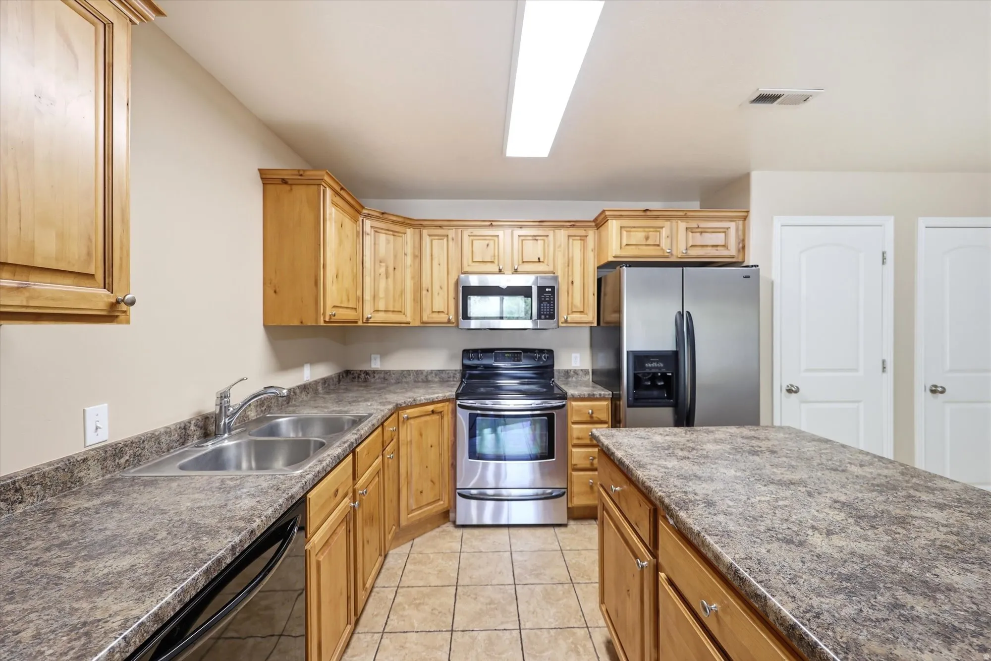 Kitchen featuring stainless steel appliances, dark countertops, and light tile patterned floors