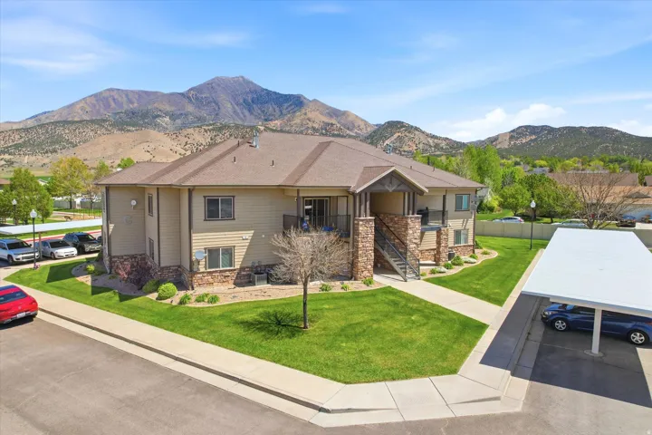 View of front of home with stone siding, a front yard, a mountain view, and uncovered parking