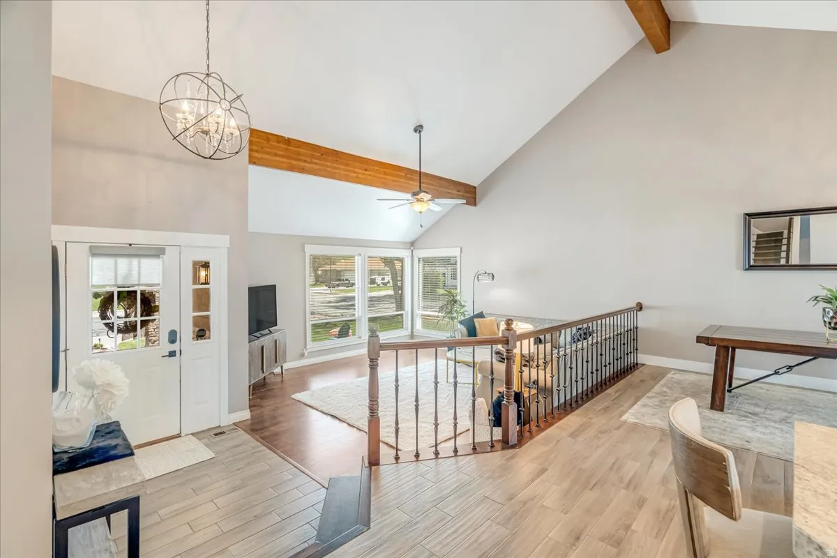 Hallway with an upstairs landing, light wood-style floors, and suspended lighting