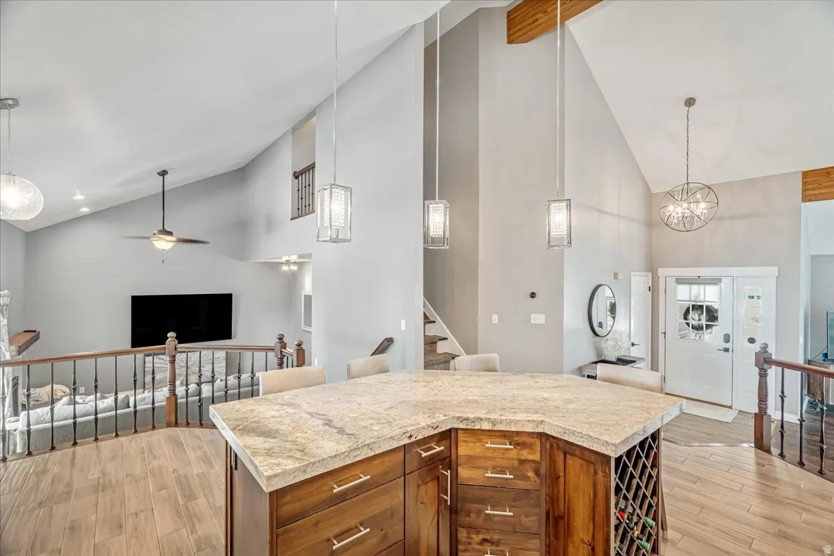 Kitchen with lofted ceiling, open floor plan, light wood finished floors, hanging lights, and light countertops