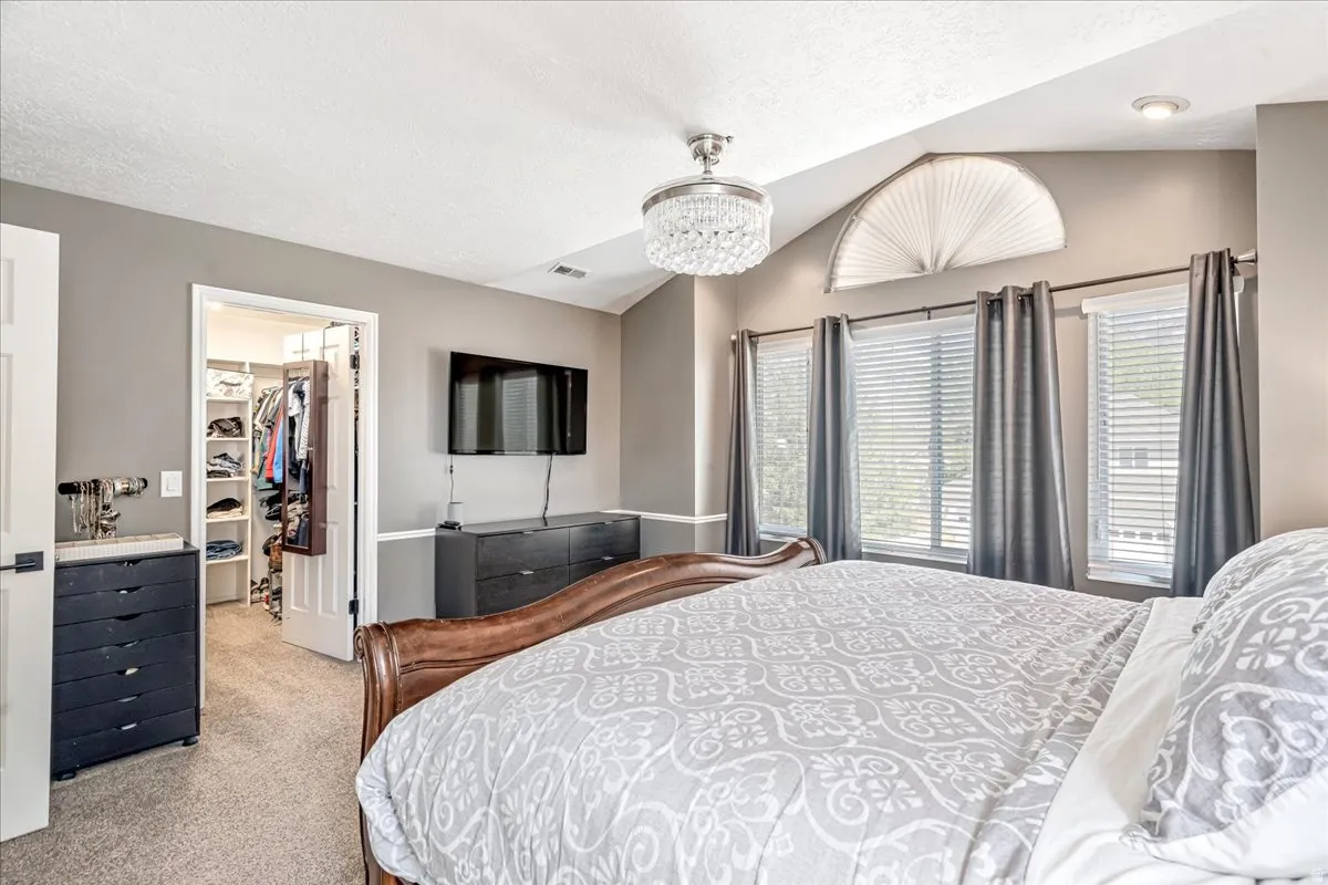 Bedroom featuring light colored carpet, a walk in closet, and a chandelier