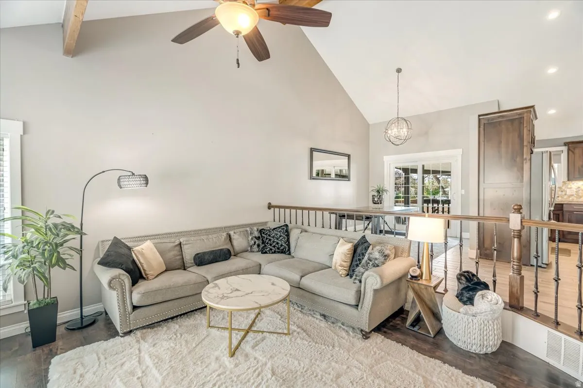 Living room with lofted ceiling, wood finished floors, a ceiling fan, and hanging lights