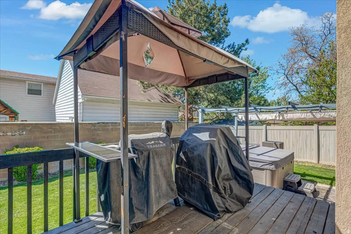 Deck with area for grilling, a fenced backyard, a gazebo, and a hot tub