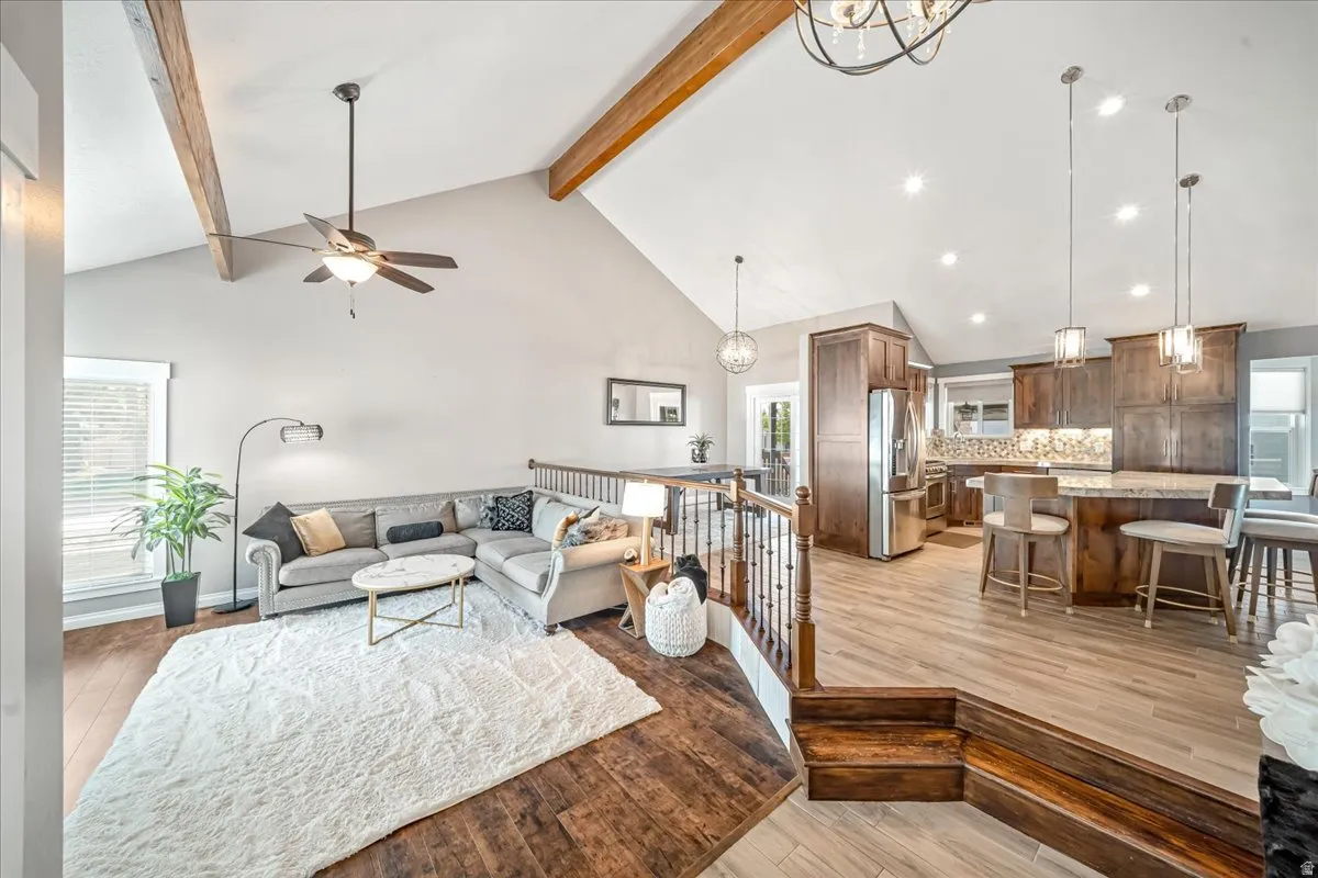 Living room with light wood-style flooring, hanging lights, and a ceiling fan
