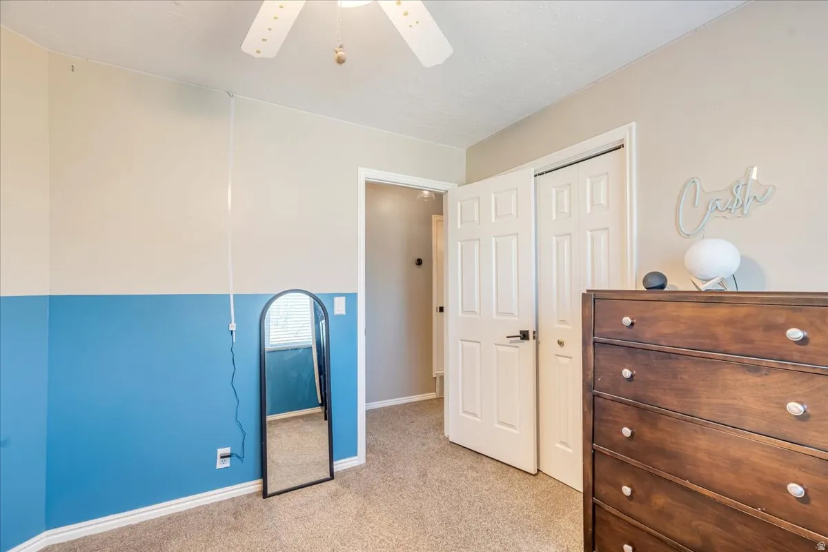 Bedroom with light carpet, a ceiling fan, and a closet