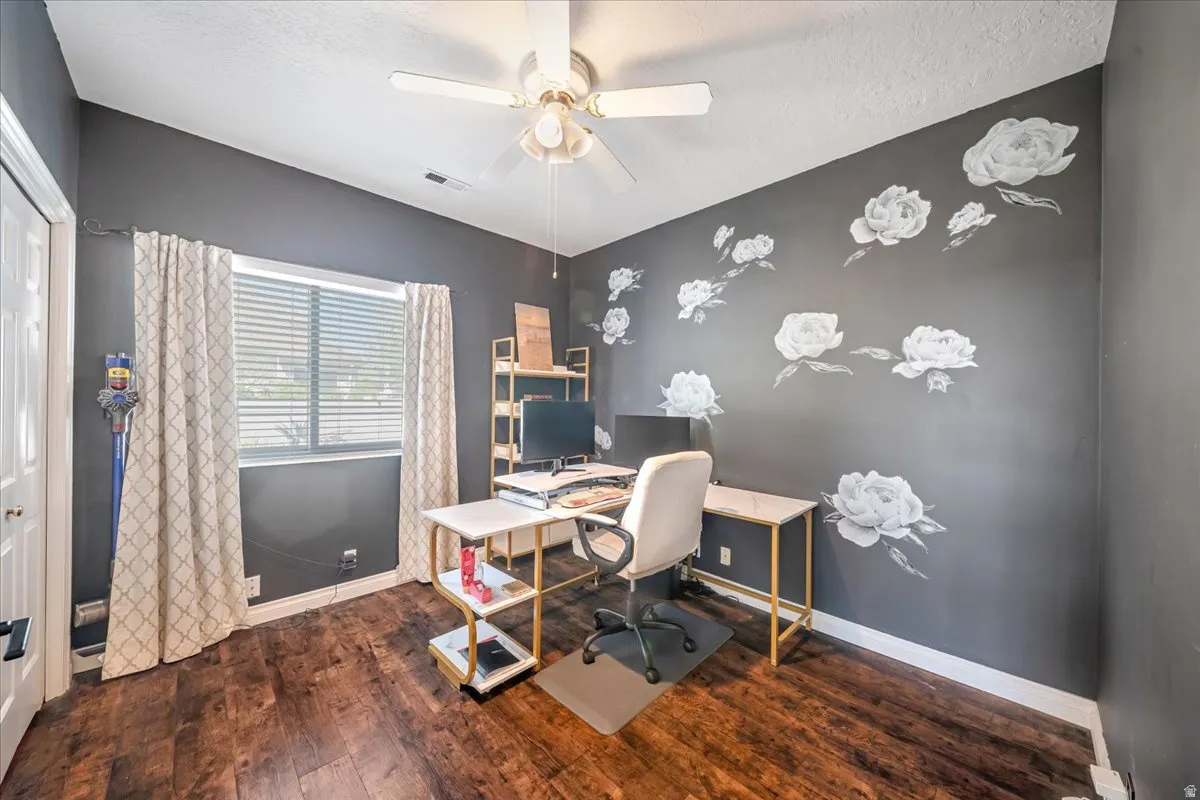 Office with ceiling fan, dark wood-style floors, a textured ceiling, and an accent wall