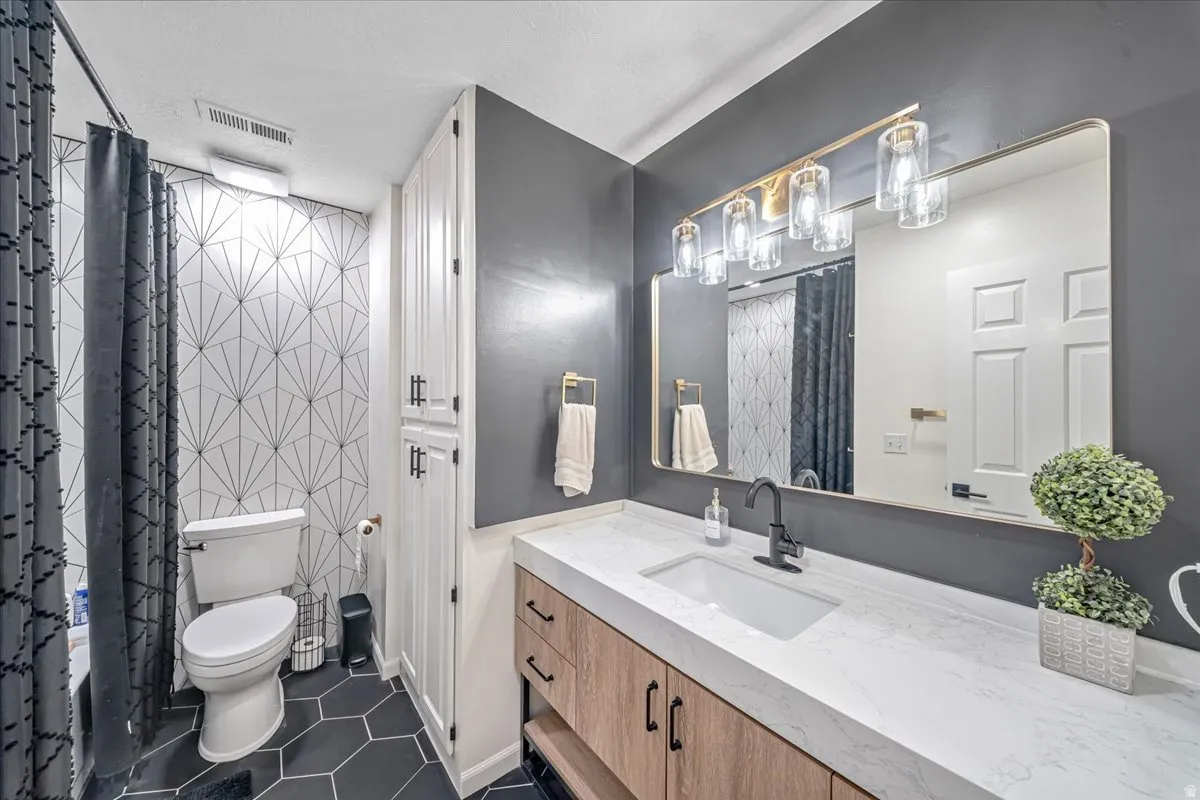 Full bathroom with vanity and dark tile patterned floors