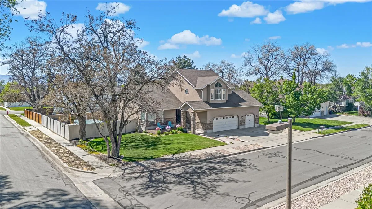 Traditional-style house featuring concrete driveway, stone siding, a garage, stucco siding, and a shingled roof