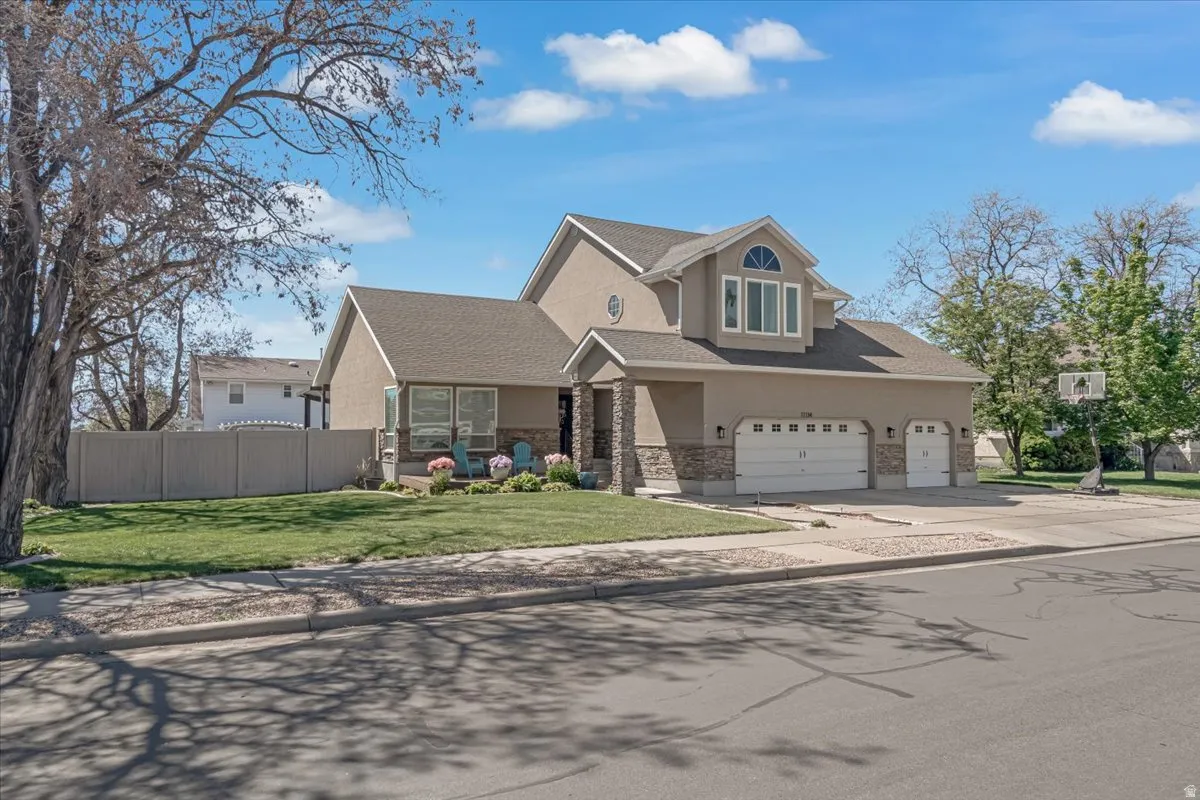 View of front of home featuring driveway, stucco siding, a shingled roof, stone siding, and an attached garage